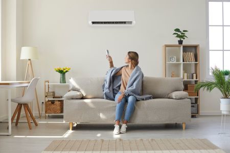 woman sitting on couch pointing at ac unit