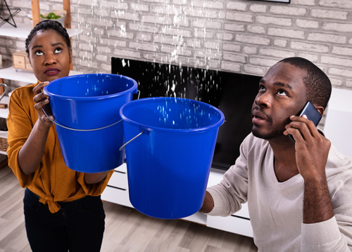 Couple holding water leaking from roof